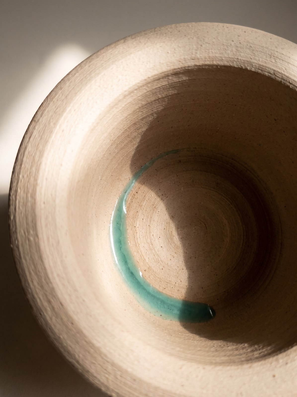 Looking down into a scooped clay well with sea-glass glaze pooling at the bottom