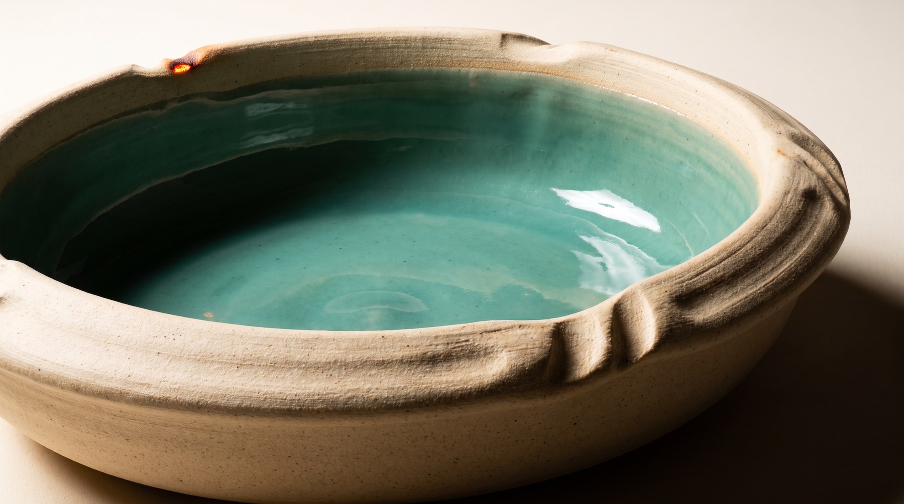 A clay basin brimming to the rim with luminous sea-glass celadon glaze